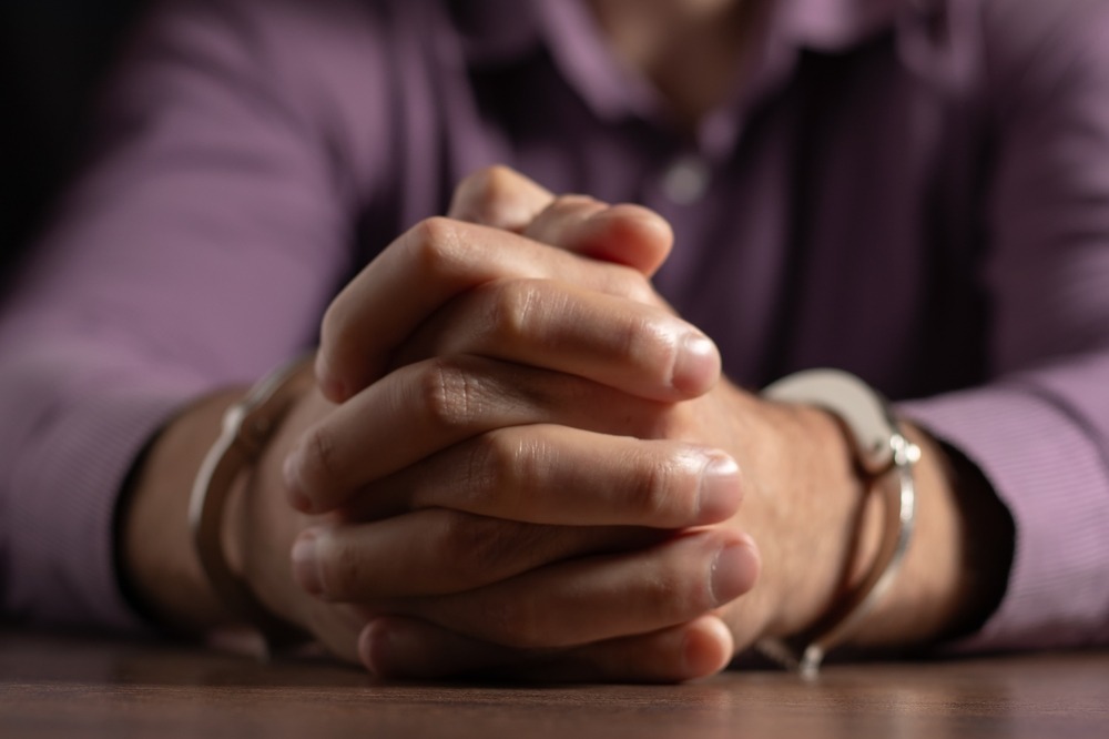 A man in handcuffs at an interrogation table. What is the difference between drug possession and drug trafficking?