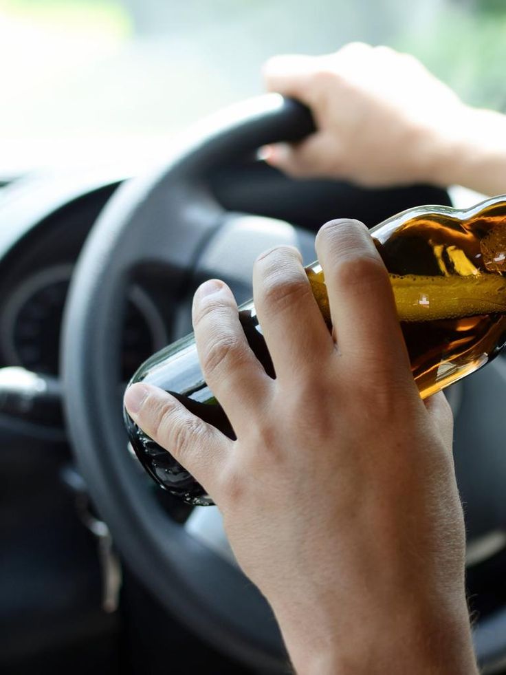 A driver holds a beer bottle while behind the wheel. In Washington, DUI is the legal term used for impaired driving, although many people still refer to the offense as DWI. 