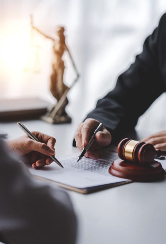 A criminal defense lawyer reviews legal documents with a client during a consultation about charges and employment concerns.